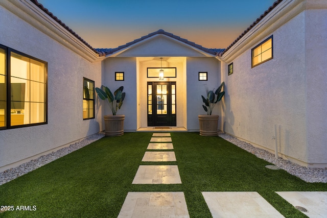 exterior entry at dusk featuring a yard and french doors