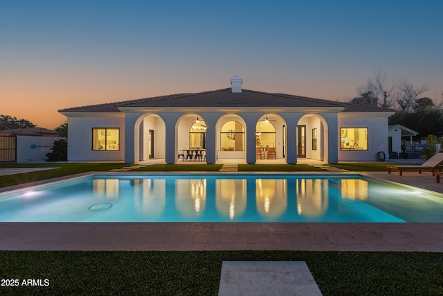 pool at dusk featuring a patio