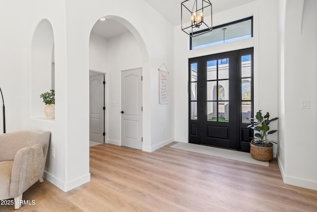 foyer featuring an inviting chandelier, light hardwood / wood-style flooring, and a towering ceiling