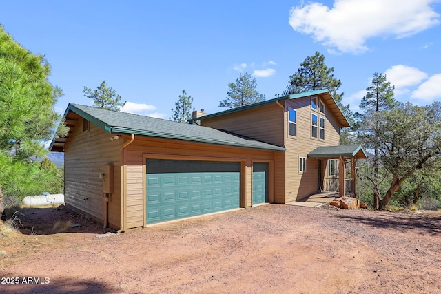 view of front of house with a garage, roof with shingles, driveway, and a chimney