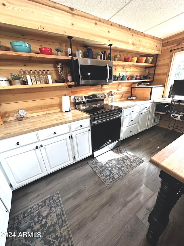 kitchen with electric stove, wood walls, white cabinetry, and wood counters