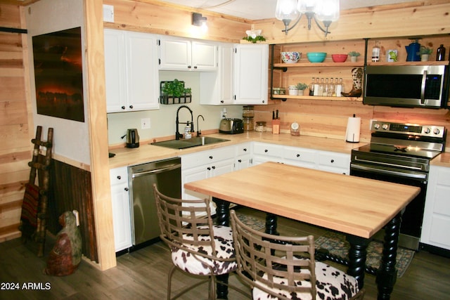 kitchen with white cabinetry, dark hardwood / wood-style flooring, stainless steel appliances, sink, and a notable chandelier