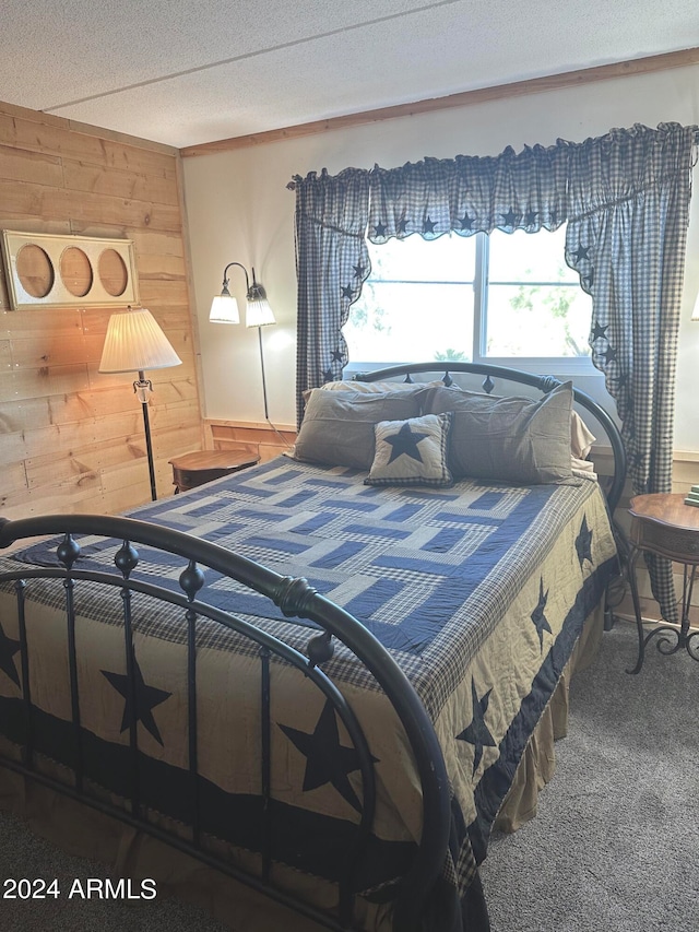 carpeted bedroom featuring a textured ceiling and wooden walls