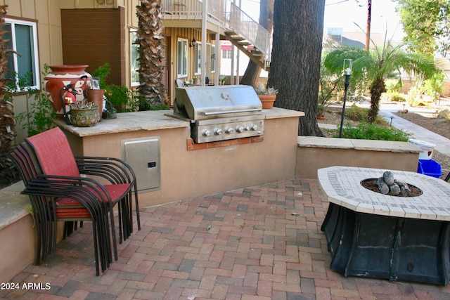 view of patio with grilling area, an outdoor fire pit, and an outdoor kitchen