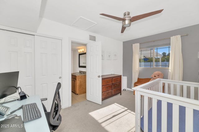 carpeted bedroom with ceiling fan, a nursery area, and a closet