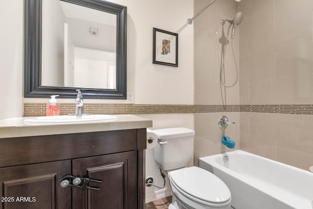 full bathroom featuring toilet, vanity, decorative backsplash, and tiled shower / bath combo