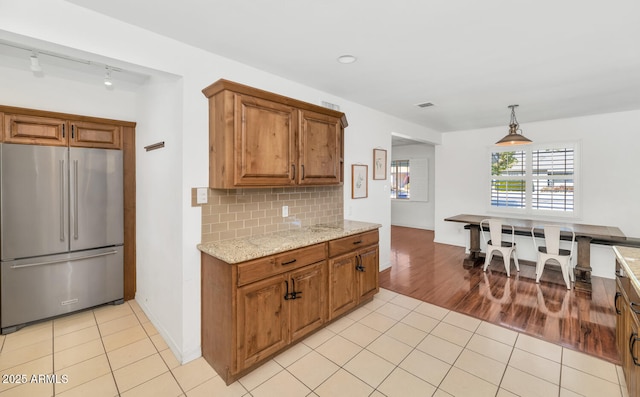 kitchen with decorative light fixtures, light tile patterned floors, decorative backsplash, and high quality fridge