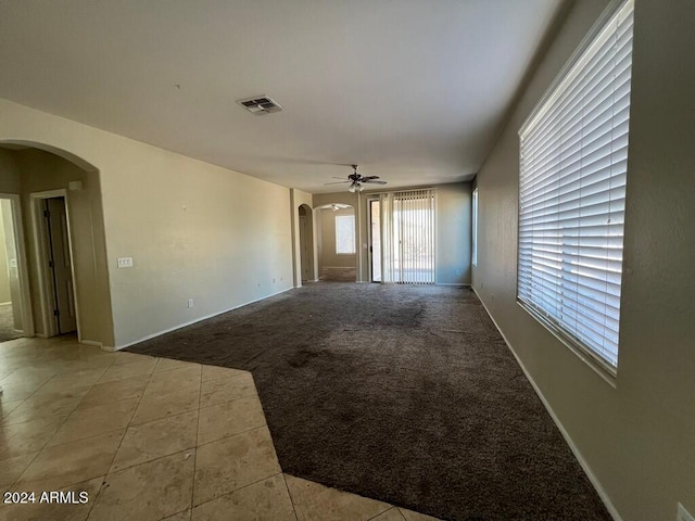3030 S 102nd Ln, Tolleson, AZ 85353 - carpeted empty room with arched walkways, ceiling fan, and tile patterned flooring