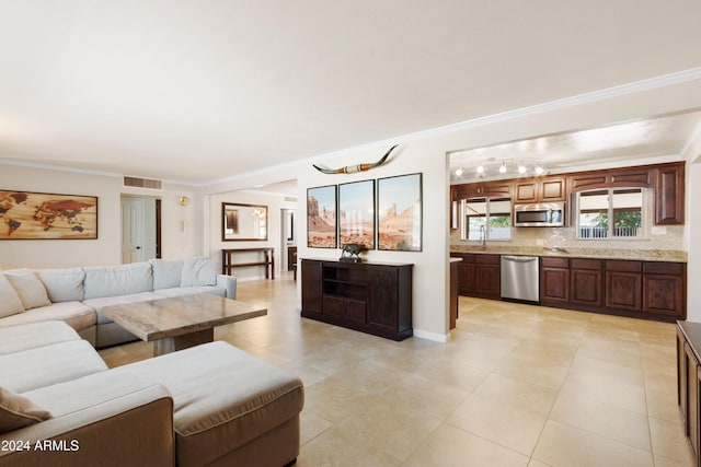 living room featuring crown molding, sink, and light tile patterned floors