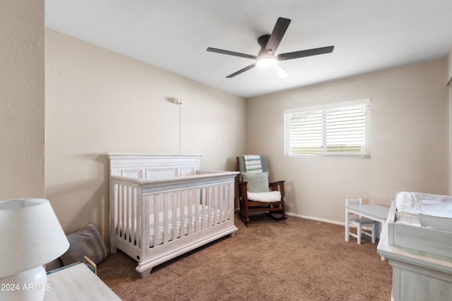 carpeted bedroom with a crib and ceiling fan