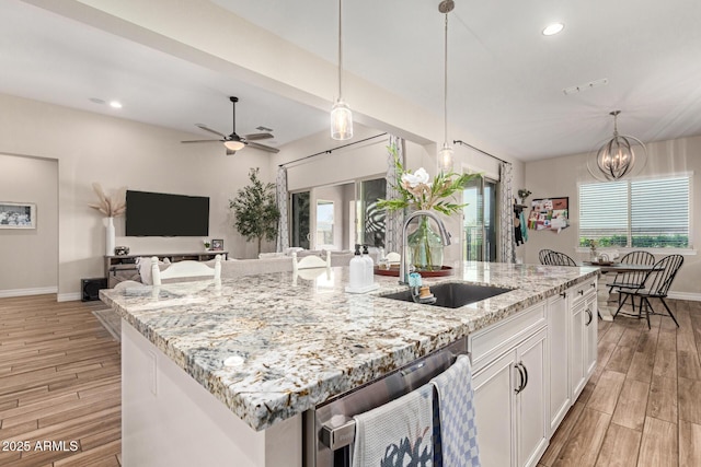 kitchen featuring a center island with sink, sink, ceiling fan with notable chandelier, and white cabinets