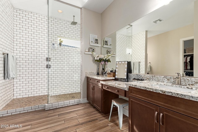 bathroom featuring hardwood / wood-style flooring, vanity, and a tile shower