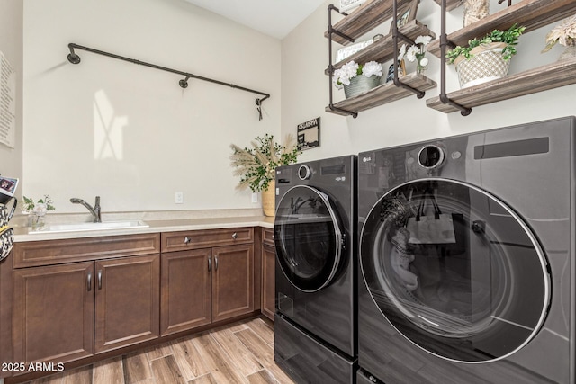 laundry room with cabinets, independent washer and dryer, sink, and light hardwood / wood-style floors