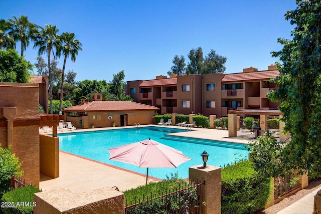 community pool with a patio area and fence