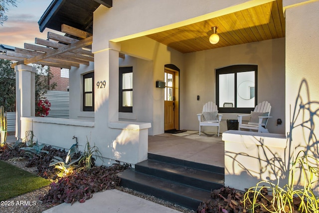 exterior entry at dusk with a pergola and a patio