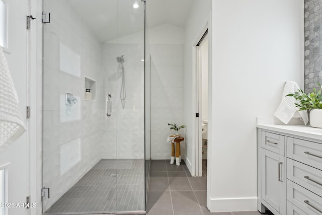 bathroom with vaulted ceiling, vanity, an enclosed shower, toilet, and tile patterned floors