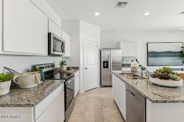 kitchen featuring sink, a kitchen island with sink, stainless steel appliances, light stone countertops, and white cabinets