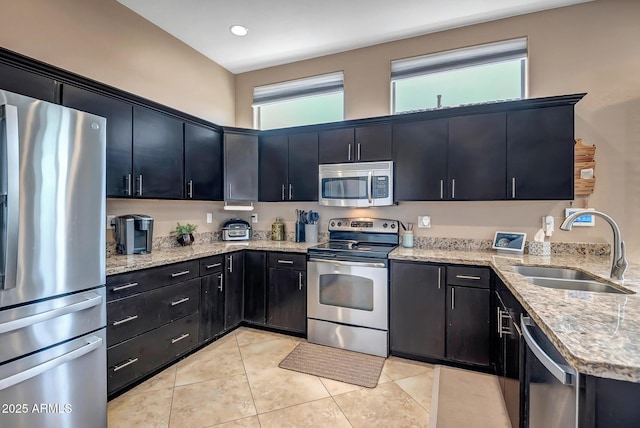 17493 W Arroyo Way, Goodyear, AZ 85338 - kitchen with stainless steel appliances, dark cabinetry, light tile patterned floors, light stone counters, and recessed lighting