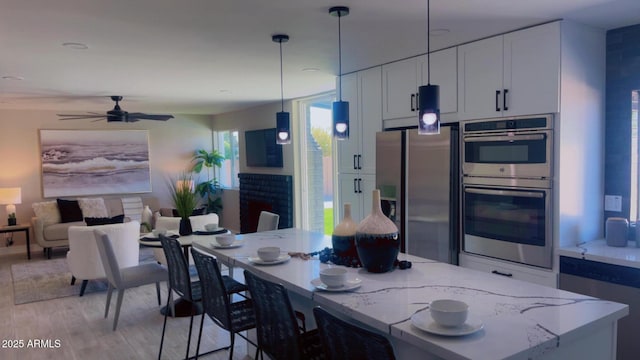 4509 E La Puente Ave, Phoenix, AZ 85044 - kitchen featuring appliances with stainless steel finishes, light stone counters, light wood-style flooring, hanging light fixtures, and white cabinets