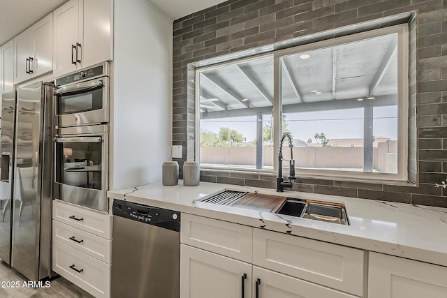 4509 E La Puente Ave, Phoenix, AZ 85044 - kitchen featuring appliances with stainless steel finishes, white cabinetry, a sink, and light stone countertops