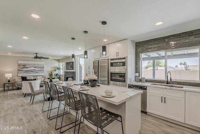 4509 E La Puente Ave, Phoenix, AZ 85044 - kitchen with stainless steel appliances, a sink, light wood-style floors, white cabinets, and decorative backsplash