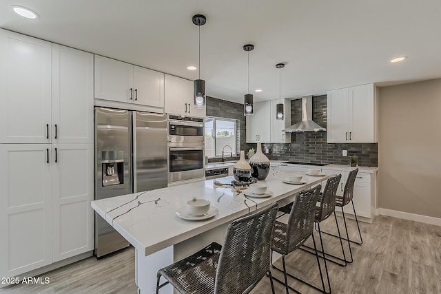 4509 E La Puente Ave, Phoenix, AZ 85044 - kitchen featuring wall chimney range hood, appliances with stainless steel finishes, light wood-type flooring, backsplash, and a kitchen breakfast bar