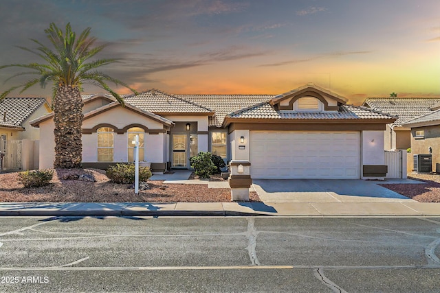 mediterranean / spanish-style house with central AC and a garage