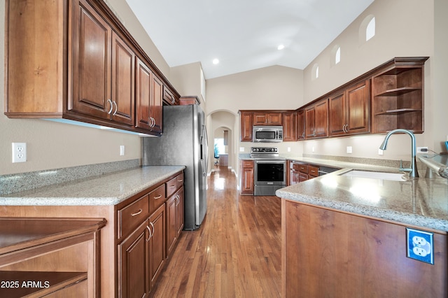 kitchen with vaulted ceiling, appliances with stainless steel finishes, dark hardwood / wood-style floors, sink, and kitchen peninsula