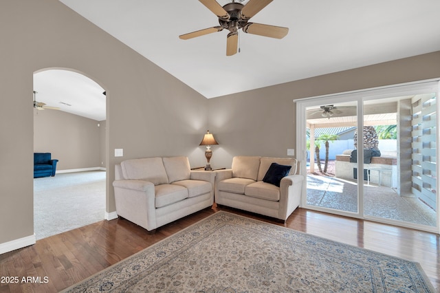 living room featuring dark wood-type flooring, ceiling fan, and vaulted ceiling