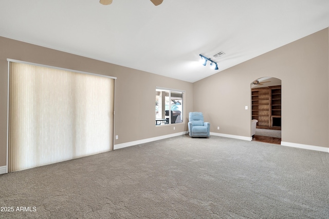 interior space with rail lighting, lofted ceiling, carpet flooring, and ceiling fan