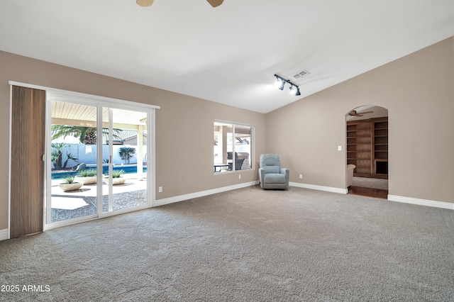 unfurnished room with vaulted ceiling, rail lighting, carpet flooring, and ceiling fan