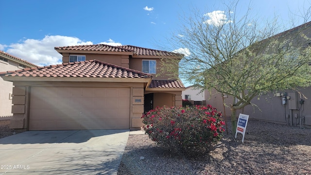 mediterranean / spanish house with driveway, an attached garage, a tile roof, and stucco siding