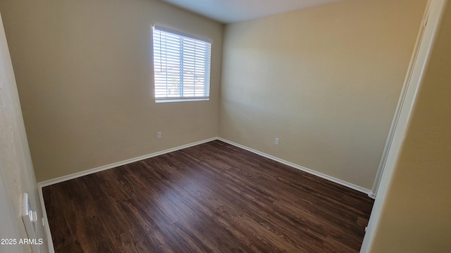 empty room with dark wood finished floors and baseboards