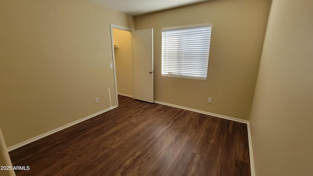 empty room featuring dark wood finished floors and baseboards