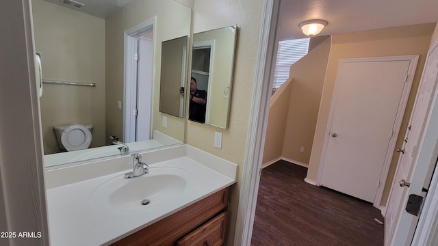 bathroom with toilet, visible vents, wood finished floors, and vanity