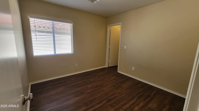 unfurnished room with dark wood finished floors and baseboards