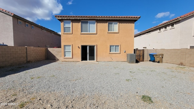 back of house featuring a fenced backyard, central AC, and stucco siding