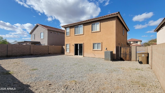 back of property with a gate, stucco siding, a fenced backyard, and central AC unit