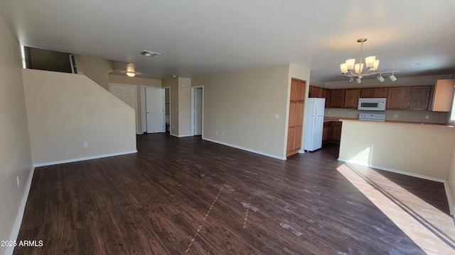 unfurnished living room featuring a chandelier, dark wood-type flooring, visible vents, and baseboards