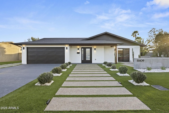 view of front of property with aphalt driveway, a front yard, fence, and an attached garage