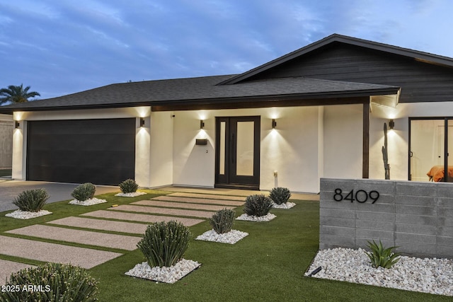 view of front of home with a garage, a shingled roof, driveway, stucco siding, and a front yard