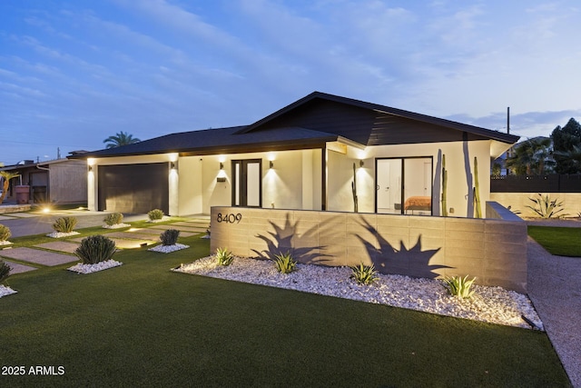 view of front facade with an attached garage, a front lawn, and stucco siding