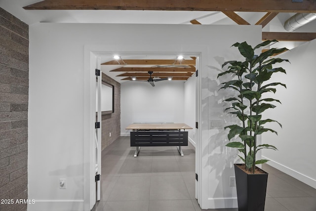 hall with brick wall, tile patterned flooring, beam ceiling, and baseboards