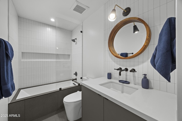 full bathroom featuring tasteful backsplash, visible vents, toilet, tiled shower / bath combo, and tile walls