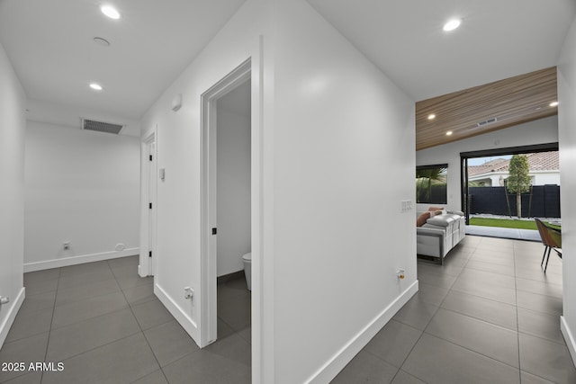 hall featuring tile patterned floors, baseboards, visible vents, and recessed lighting