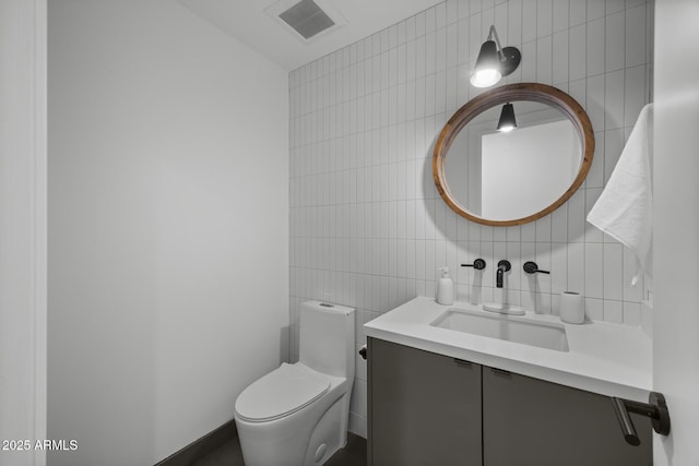 half bathroom with tile walls, visible vents, decorative backsplash, toilet, and vanity