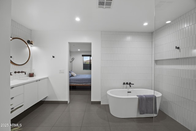 ensuite bathroom featuring vanity, visible vents, tile walls, a soaking tub, and tile patterned floors