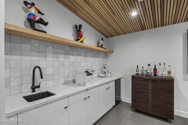 kitchen with a sink, light countertops, white cabinetry, open shelves, and backsplash