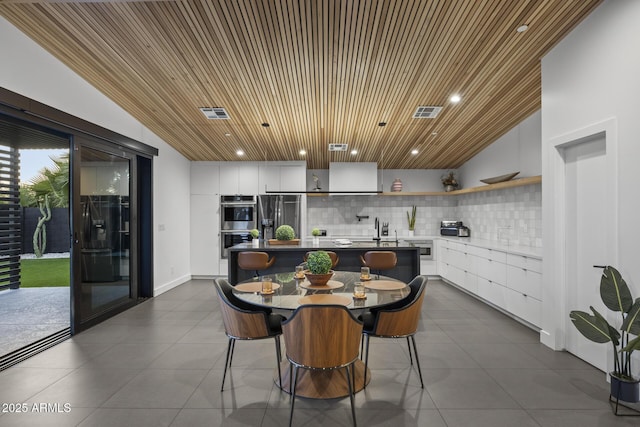 dining space featuring visible vents, dark tile patterned flooring, and wood ceiling