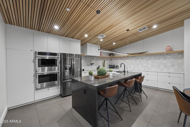 kitchen featuring stainless steel appliances, tasteful backsplash, open shelves, and visible vents